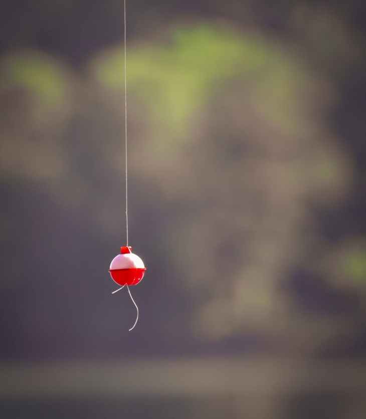 photo of a fishing bobber dangling above a blurred lake