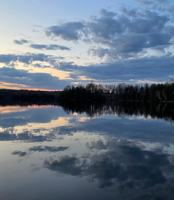 Sunset in Spring with orange and blue streaks in a sky over a still lake