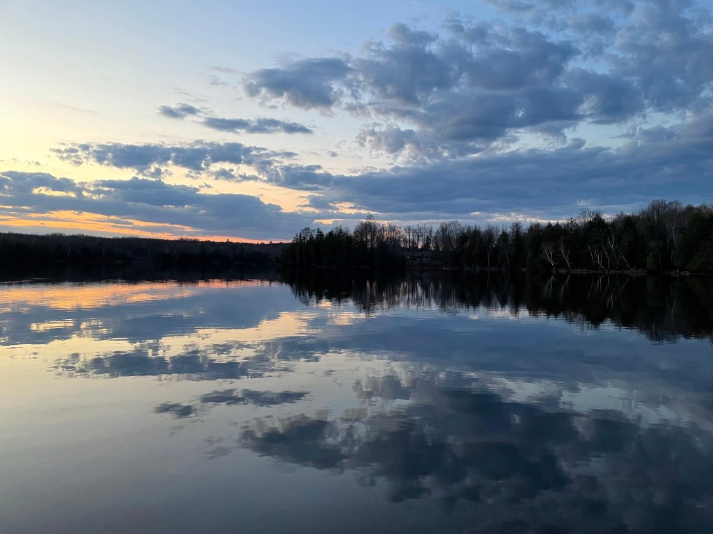 Sunset in Spring with orange and blue streaks in a sky over a still lake